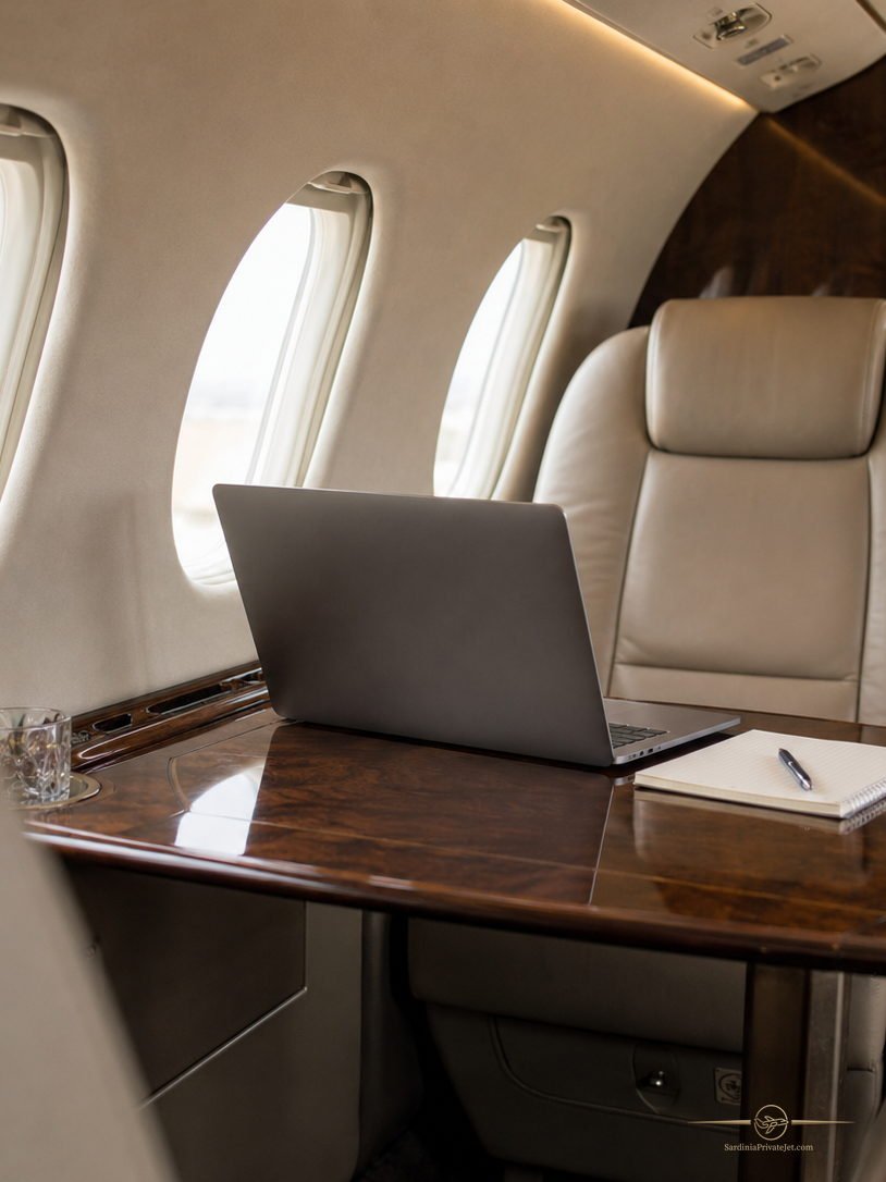 Cabina di un jet privato vista dal corridoio, poltrone in pelle e tavolini laterali